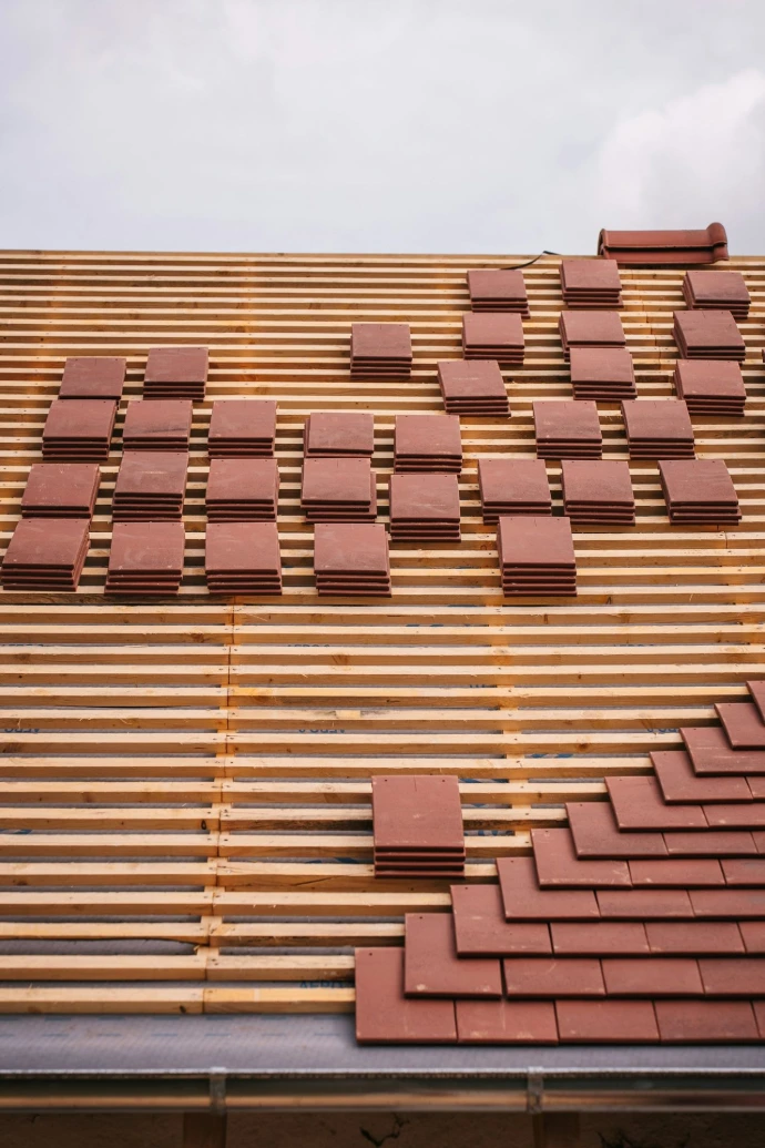 Roof tiles are being installed on a wooden frame.